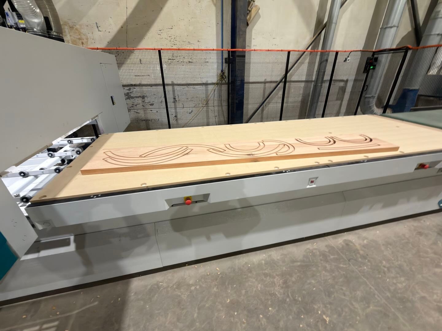 Curved parts cut by the CNC router from a solid timber board on its bed