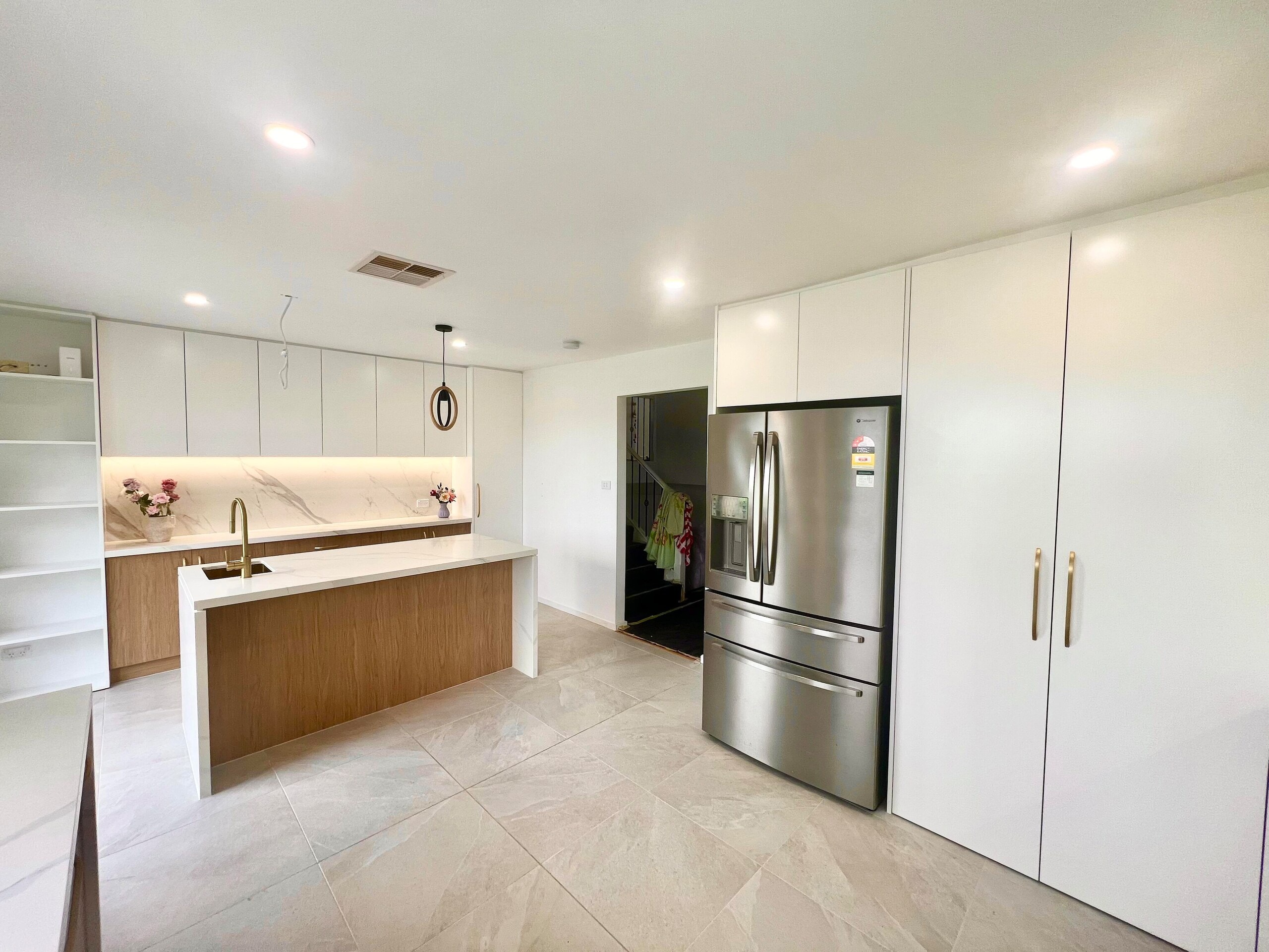 White and timber kitchen with an island, marble-look splashback and tall pantry cupboards
