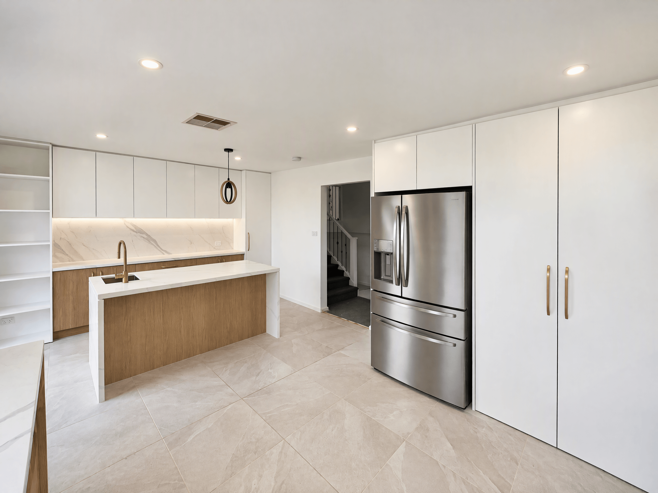 White and timber kitchen with an island, marble-look splashback and tall pantry cupboards
