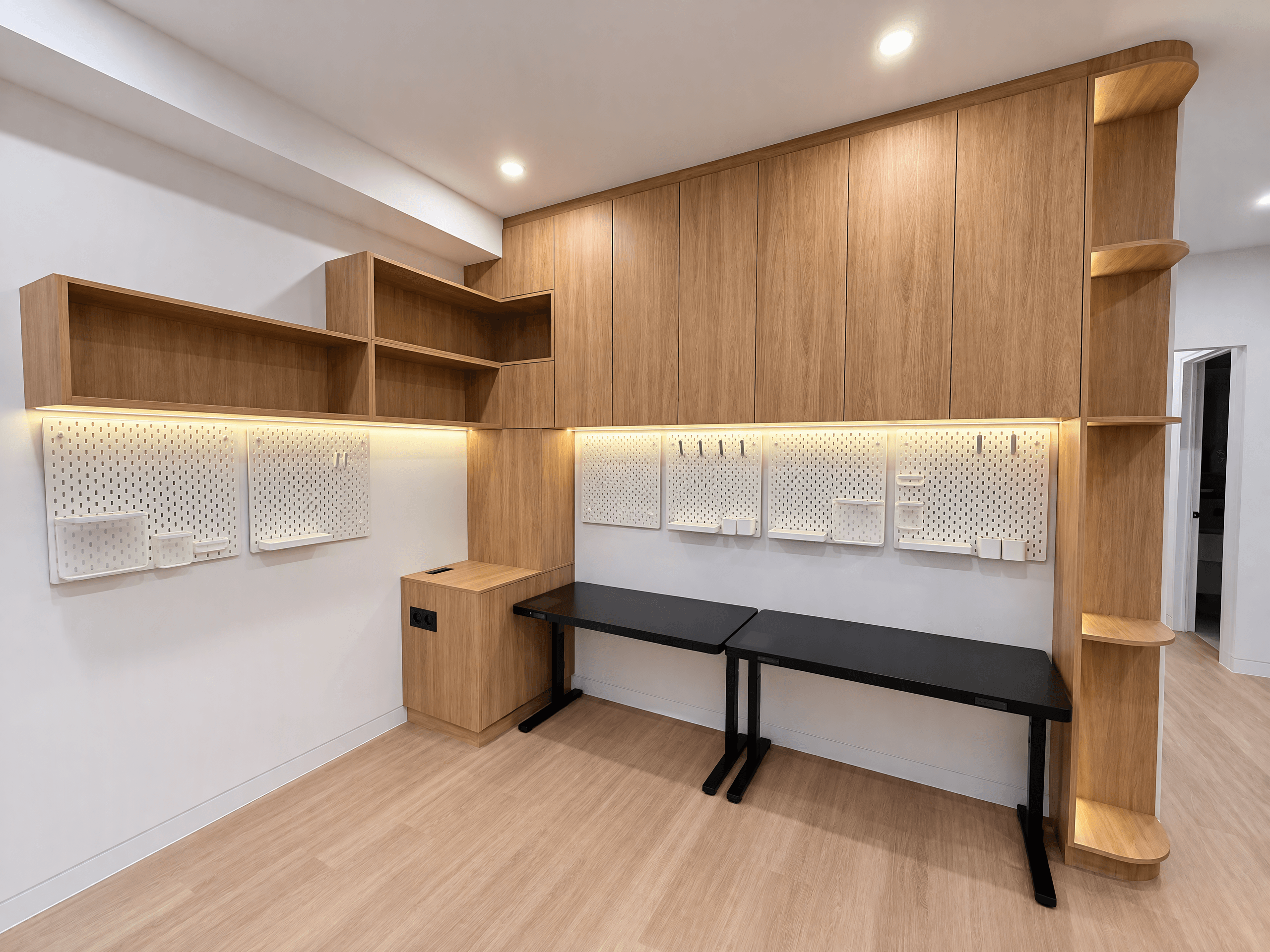 Home study with timber overhead cupboards, open shelves, a curved end shelf and lit pegboard over two desks