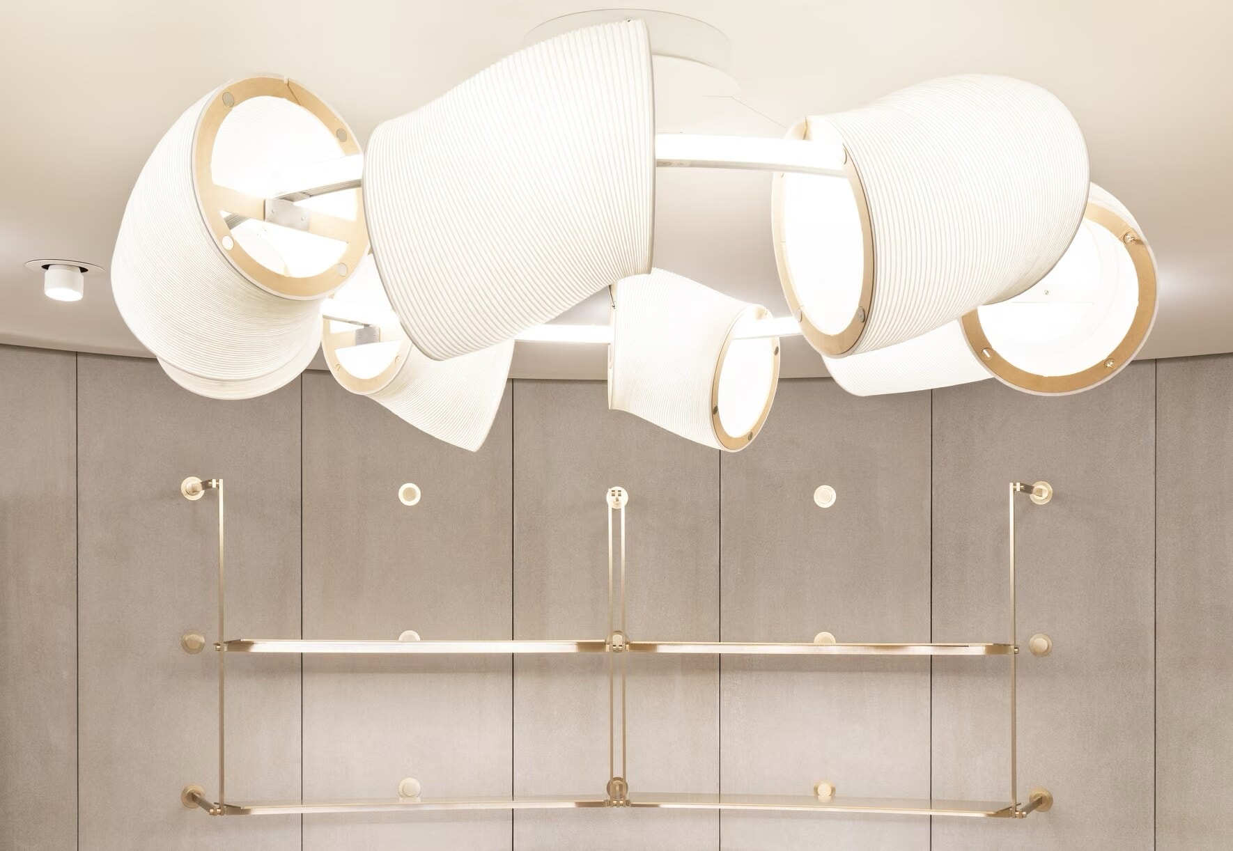Sculptural pendant light above brass rails in the Valentino boutique