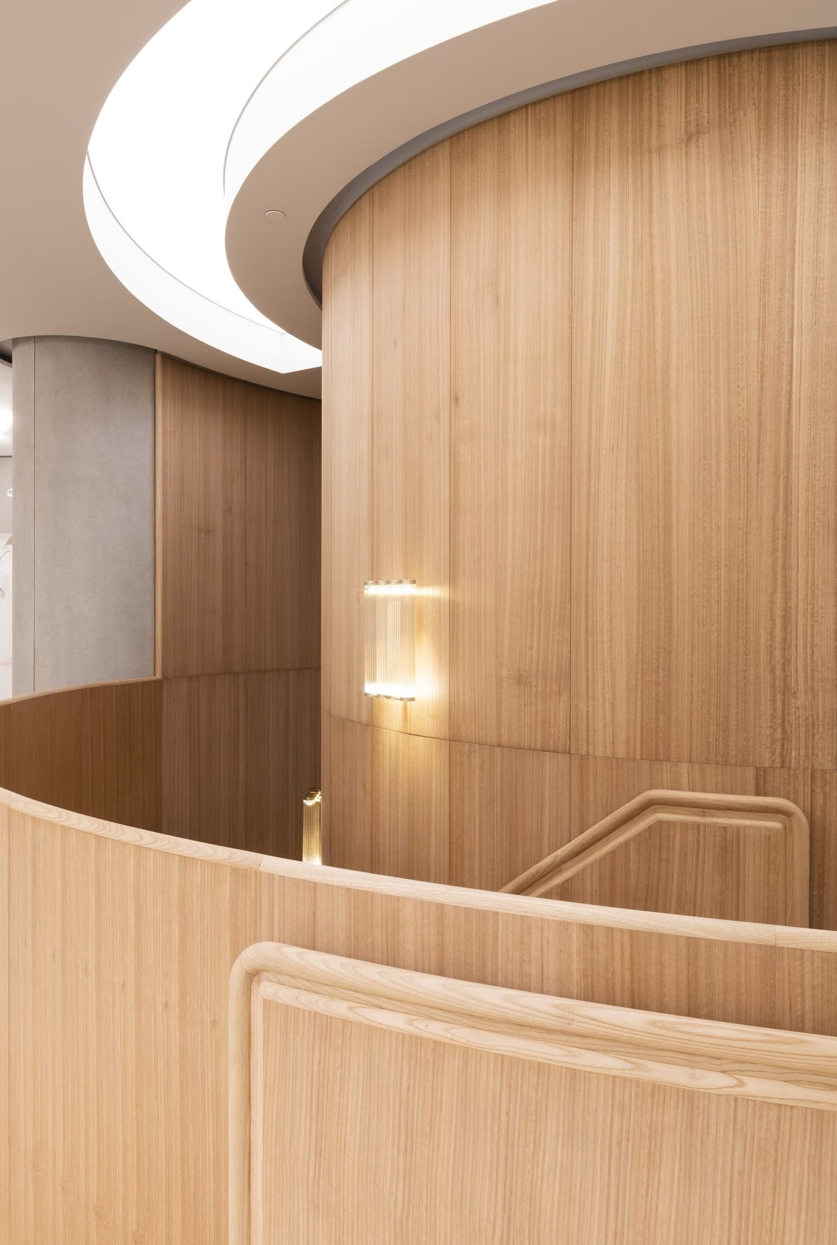 Curved timber stair wall with wall light in the Valentino boutique